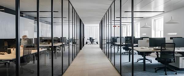 Ein moderner Arbeitsbereich, der sich durch ein elegantes, minimalistisches Design auszeichnet. Das Büro besticht durch klare Linien und ein offenes Raumkonzept mit Glastrennwänden, die ein Gefühl von Weite und Transparenz schaffen.