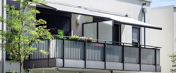 Balkon mit Markise. Ausfahrbare Markisen an modernen Balkonen. Beschatteter Terrassenbalkon eines modernen Mehrfamilienhauses.
